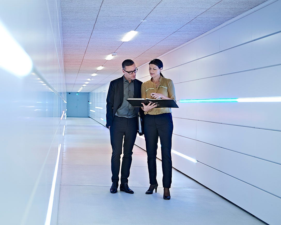 Businesswoman and man reading file in office corridor